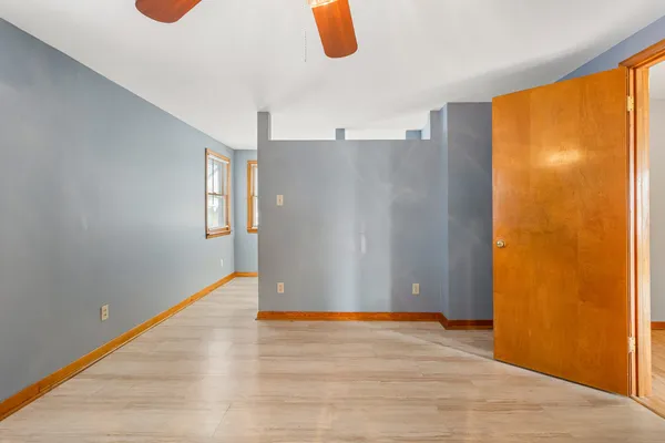 a view of an empty room with wooden floor and windows