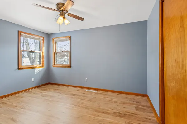 a view of an empty room with window and chandelier fan