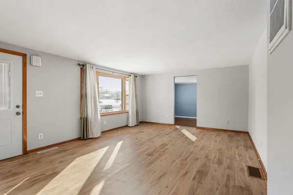 a view of an empty room with wooden floor and a window