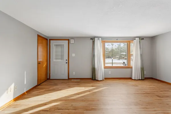 a view of an empty room with wooden floor and a window