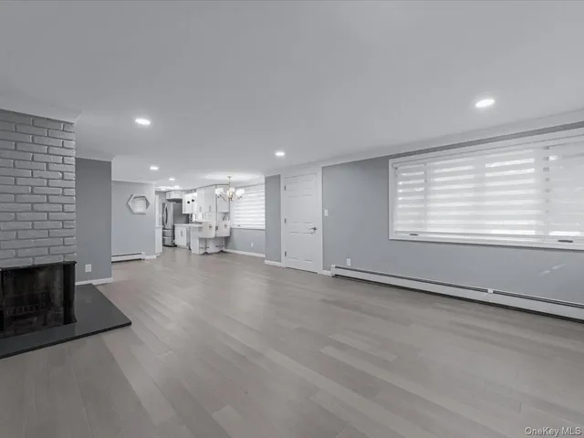 an empty room with wooden floor a fireplace and windows