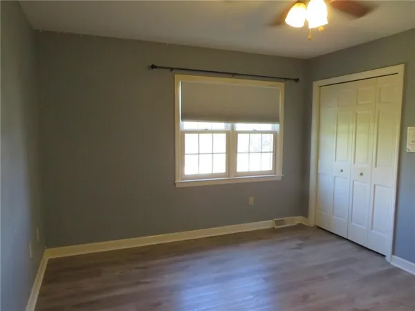 a view of an empty room with wooden floor and a mirror