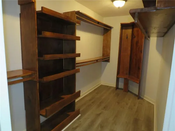 a view of an empty room with wooden floor and closet