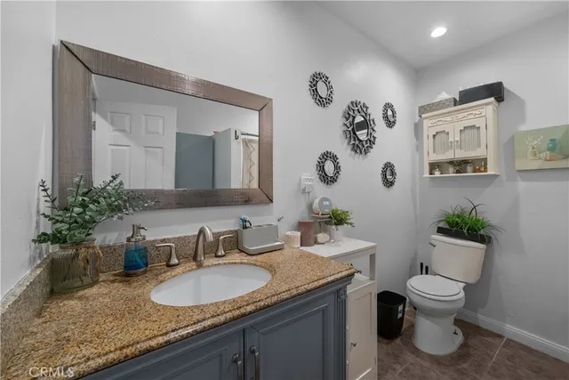 a bathroom with a granite countertop toilet sink and mirror
