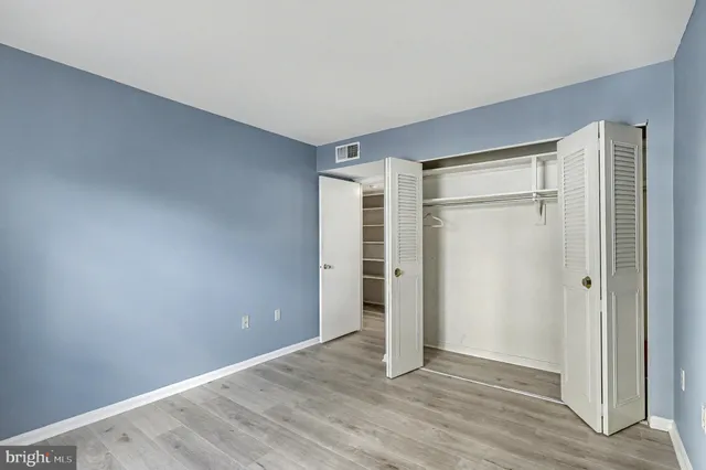 a view of an empty room with wooden floor and closet area