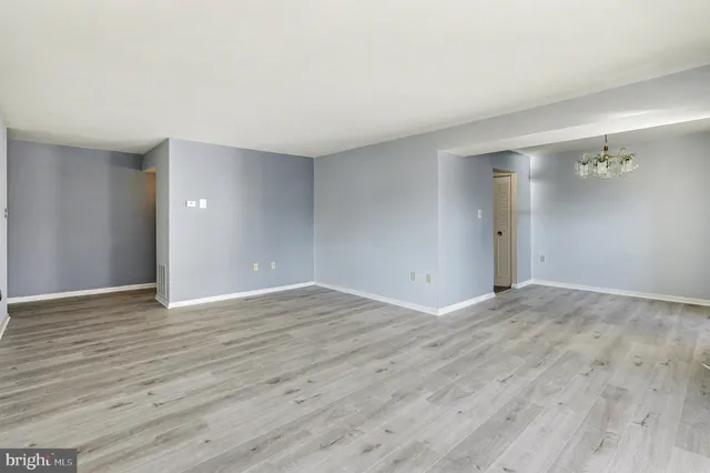 a view of an empty room with wooden floor and a bathroom