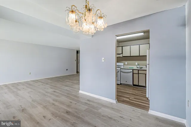 a view of a hallway with wooden floor and a kitchen