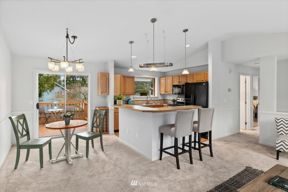 1723 225th Street Southeast Bothell, WA 98021 - Photo 8 of 40 a kitchen with stainless steel appliances kitchen island granite countertop a table chairs and a refrigerator