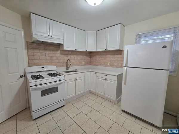 a kitchen with white cabinets and white appliances
