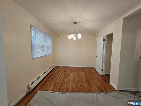 an empty room with wooden floor chandelier and windows