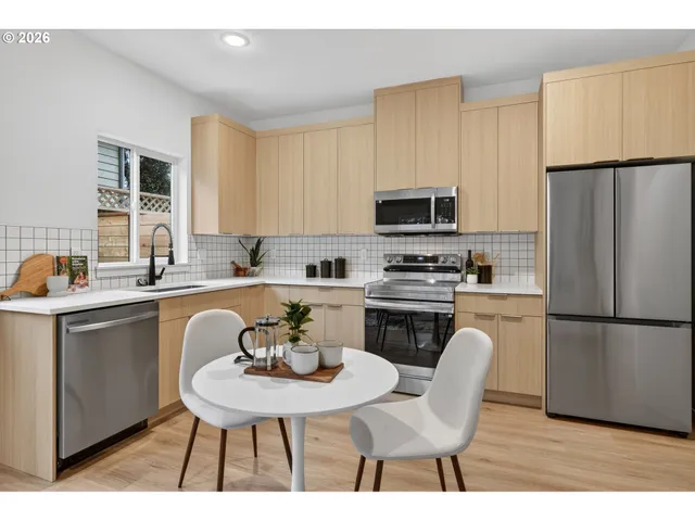 a kitchen with a refrigerator a stove a sink a dining table and chairs