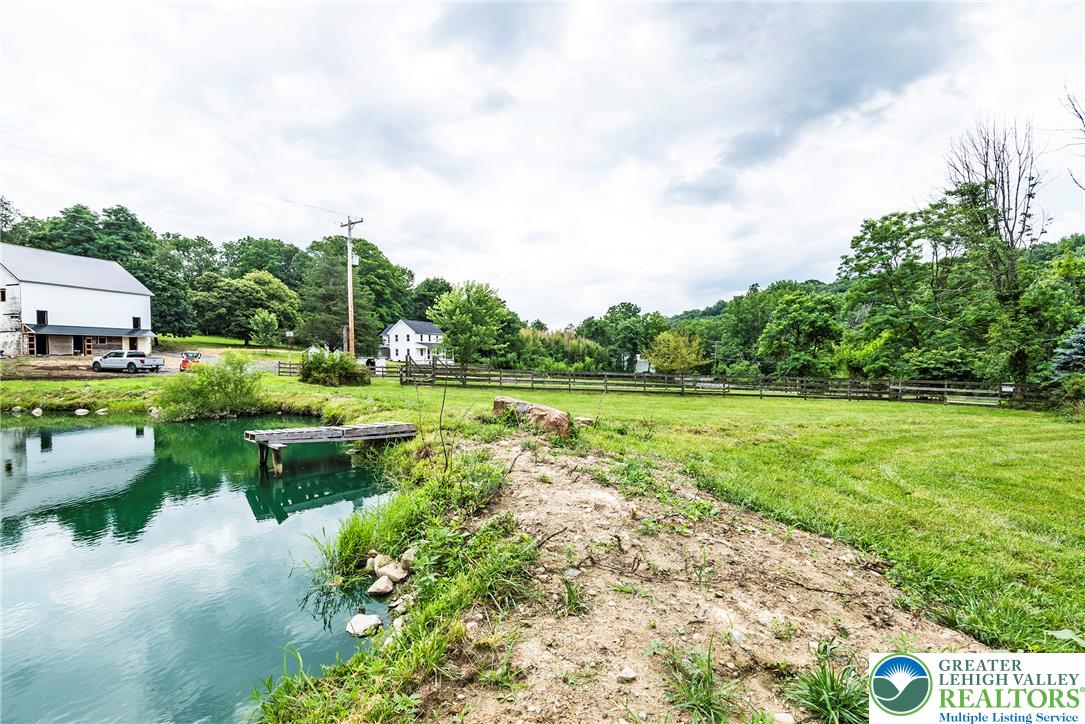 72 Allegheny Road Mount Bethel, PA 18343 - Photo 69 of 72 A tranquil pond with a simple dock offers serene waterfront enjoyment amid a lush, green landscape.