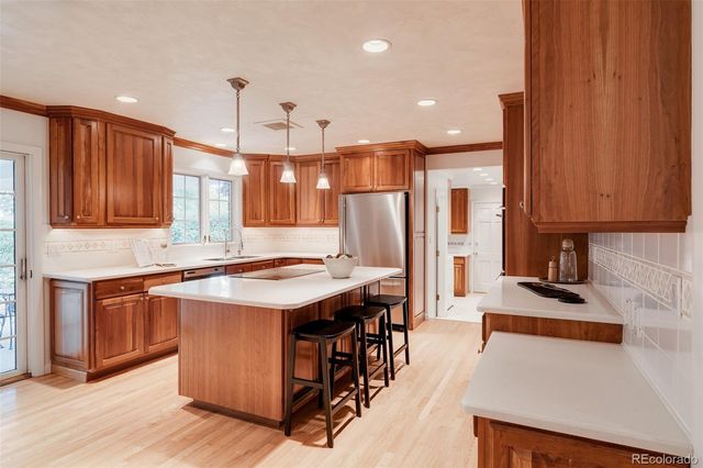 a kitchen with stainless steel appliances granite countertop a stove a refrigerator and a sink with wooden cabinets