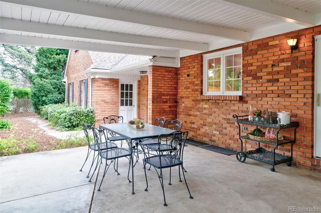 a patio with table and chairs and potted plants