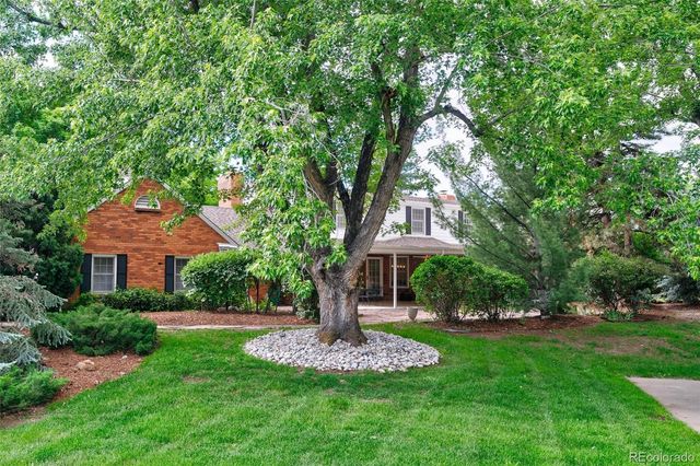 a front view of a house with a yard and tree