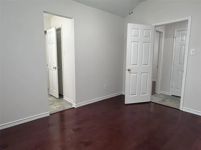 an empty room with wooden floor and closet area