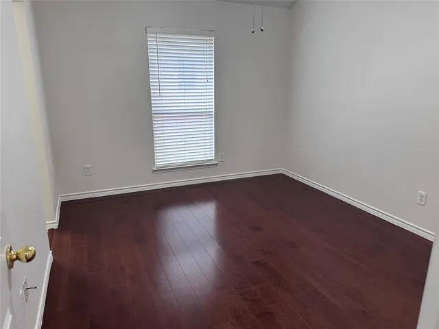 an empty room with wooden floor and a window