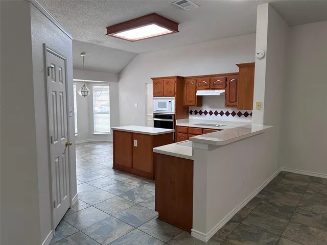a room with kitchen island a sink a stove and a refrigerator