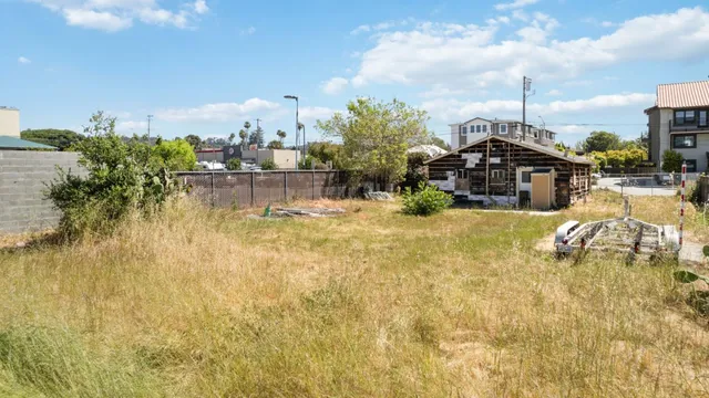 a view of a white house next to a yard with potted plants