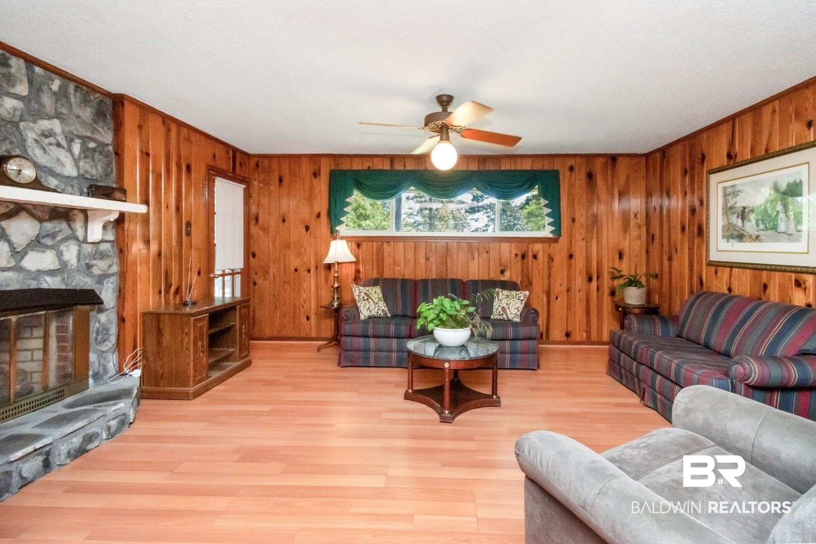 6300 Woodcrest Drive Mobile, AL 36608 - Photo 6 of 35 Living room with wood walls, a stone fireplace, a ceiling fan, and wood finished floors