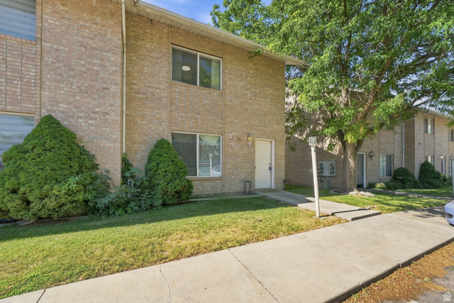 203 North Geneva Road, Unit 10 Provo, UT 84601 - Photo 19 of 30 Two-story brick exterior featuring a white entry door, multiple windows, a concrete walkway, and established landscaping