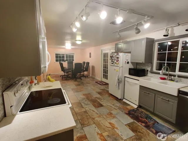 a kitchen that has a lot of white cabinets and stainless steel appliances