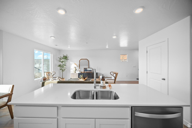 2123 Wolverine Way, Unit 2437 Washington, UT 84780 - Photo 19 of 40 Kitchen island featuring a dual-basin stainless steel sink, a modern faucet, white cabinetry, and a built-in stainless steel dishwasher
