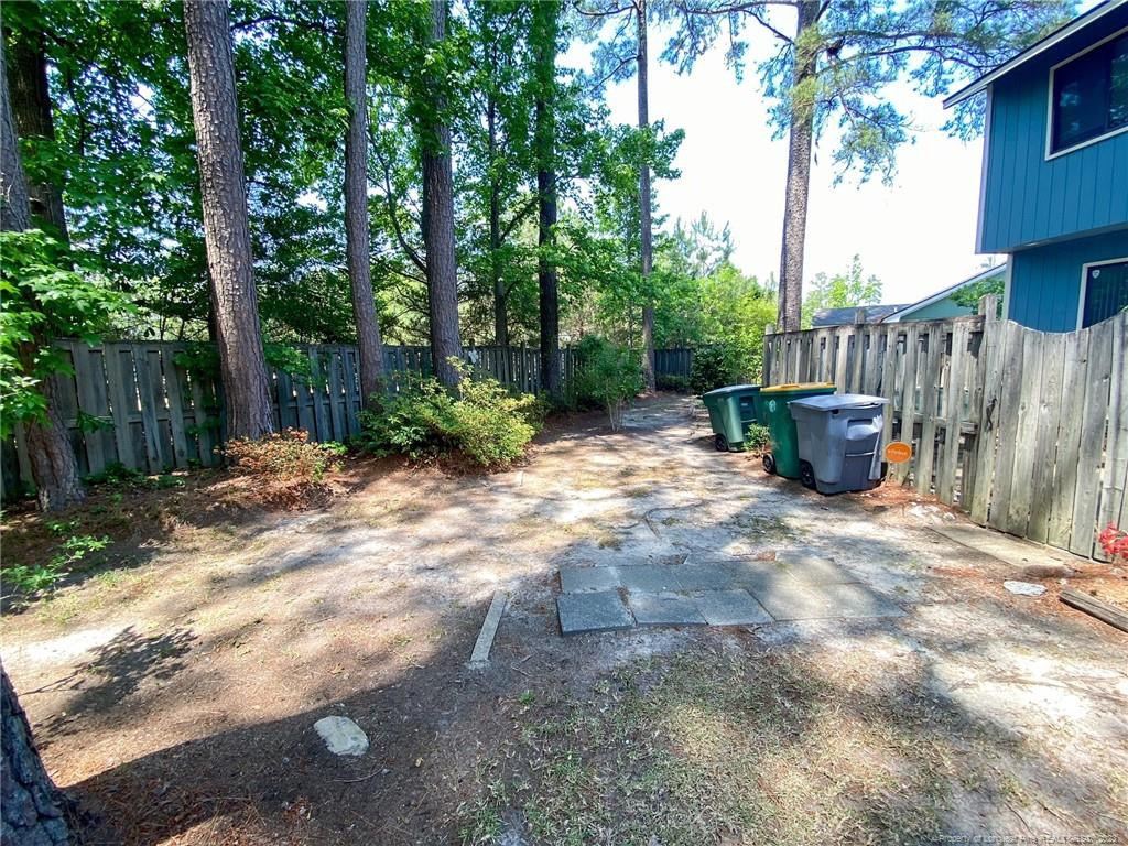 207 Charmant Road Lumberton, NC 28358 - Photo 22 of 24 a view of a backyard with table and chairs plants and trees with wooden fence