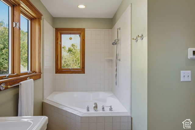 725 Canyon Road Smithfield, UT 84335 - Photo 57 of 100 Corner soaking tub with tiled surround, polished chrome fixtures, and a wall-mounted shower head