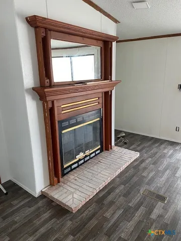 a view of an empty room with wooden floor and a fireplace