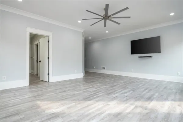 an empty room with wooden floor cabinet and windows