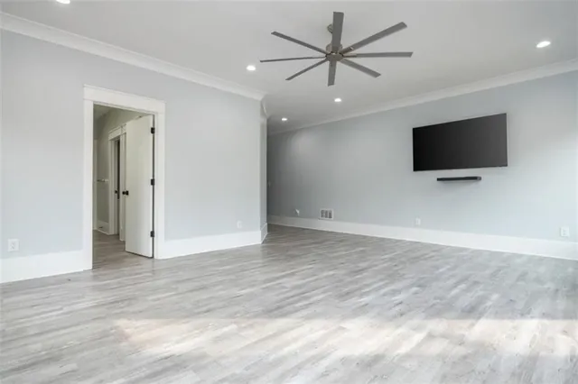 an empty room with wooden floor cabinet and windows