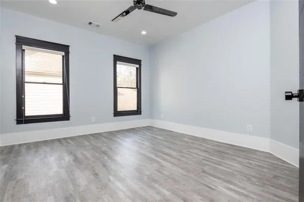 an empty room with wooden floor cabinet and windows