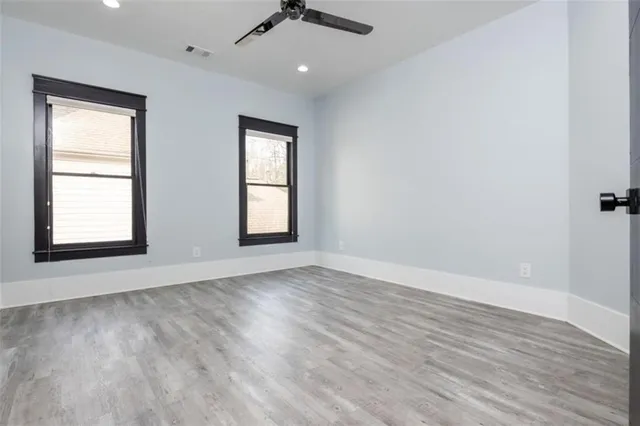 an empty room with wooden floor cabinet and windows