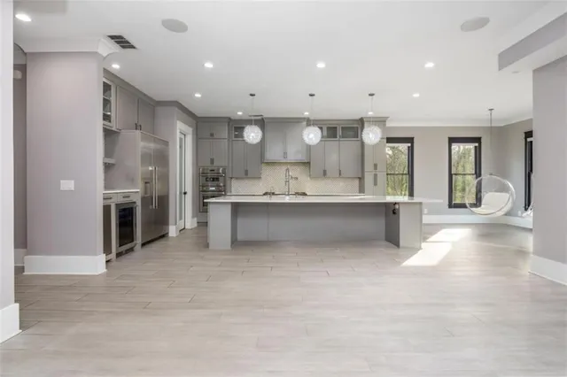 a large kitchen with stainless steel appliances a large counter top a sink and cabinets