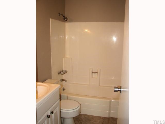 5915 Farm Gate Road Raleigh, NC 27606 - Photo 7 of 11 a bathroom with a granite countertop toilet a sink and a bathtub