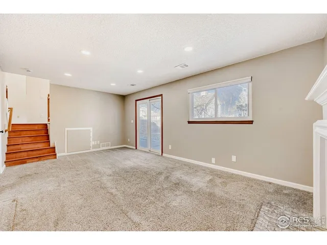 a view of an empty room with wooden floor and stairs
