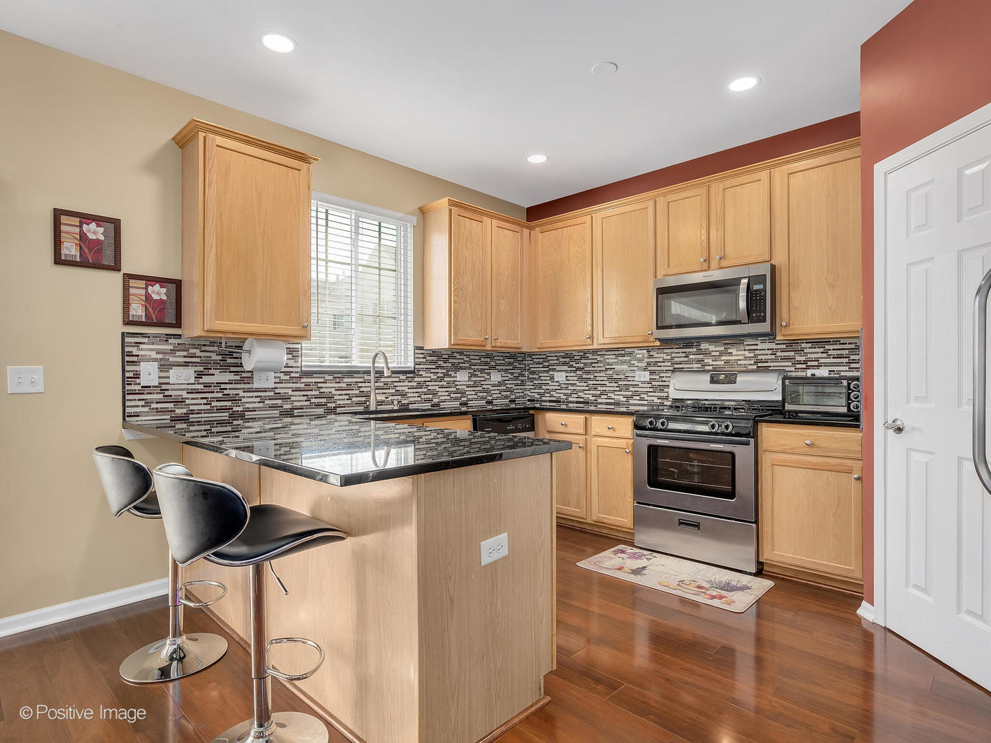 6567 Church Street Hanover Park, IL 60133 - Photo 5 of 19 a kitchen with granite countertop a stove cabinets and wooden floor