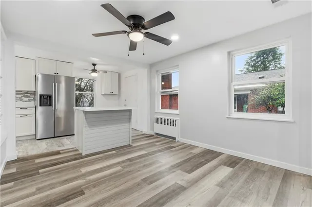a view of a kitchen with a refrigerator cabinets a ceiling fan and wooden floor
