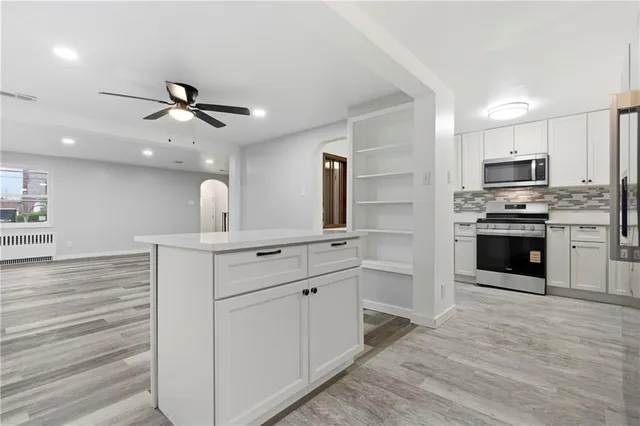 a large kitchen with cabinets wooden floor and stainless steel appliances