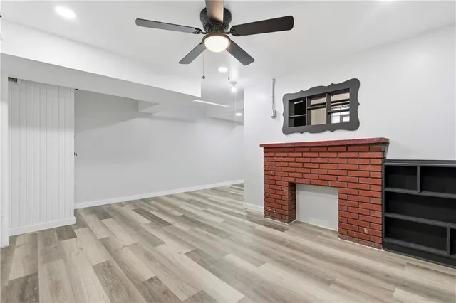 a view of an empty room with a fireplace and a ceiling fan