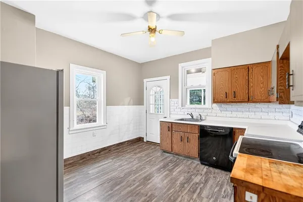 a view of a kitchen with a sink dishwasher a dining table chairs wooden floor and a kitchen view