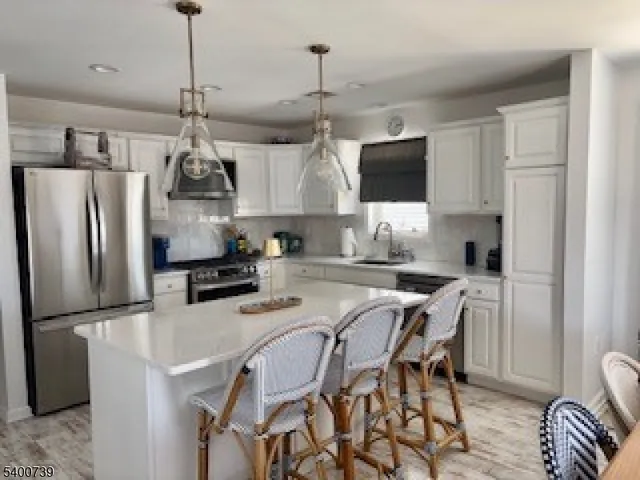 a kitchen with stainless steel appliances granite countertop a refrigerator a sink a stove a dining table and chairs