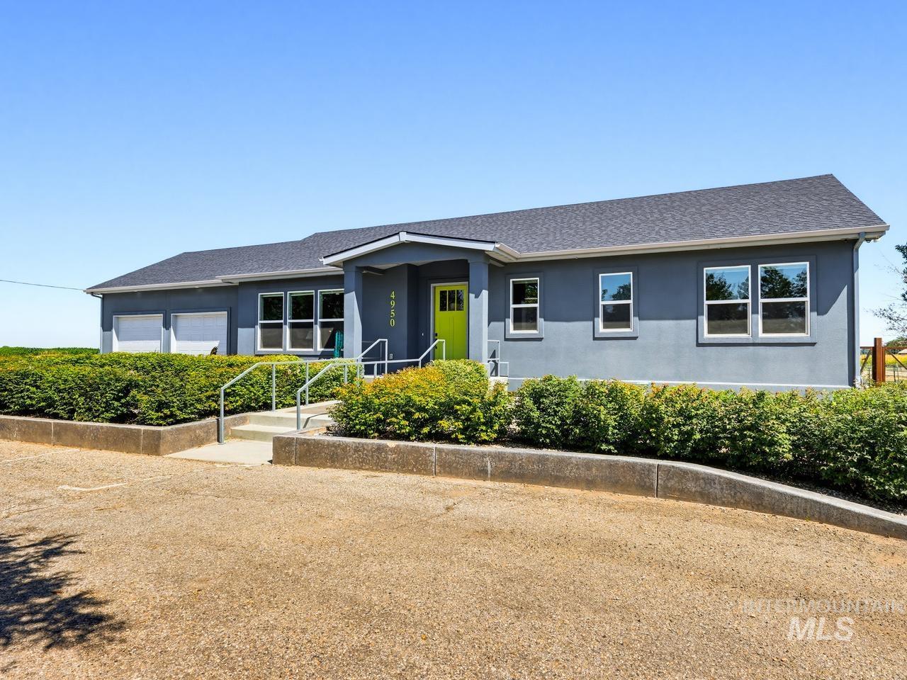 4950 West Columbia Road Nampa, ID 83687 - Photo 4 of 50 Gray stucco exterior with a bright green front door, featuring a dark shingle roof