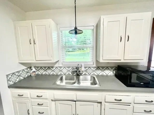 a kitchen with granite countertop white cabinets and window