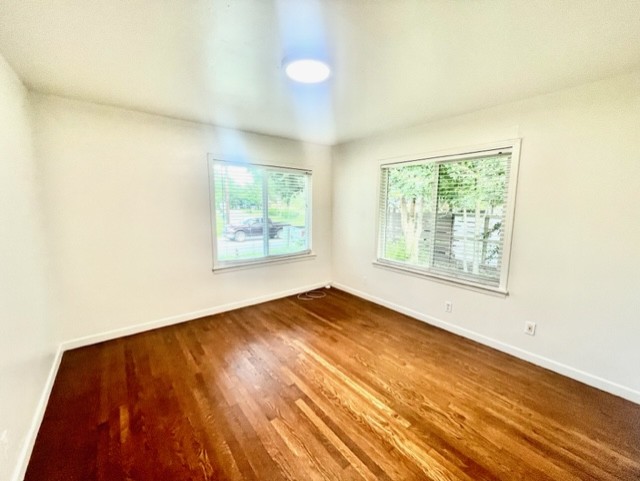 1109 Davis Street Taylor, TX 76574 - Photo 8 of 12 an empty room with wooden floor and windows