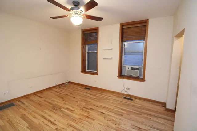 an empty room with wooden floor closet and windows