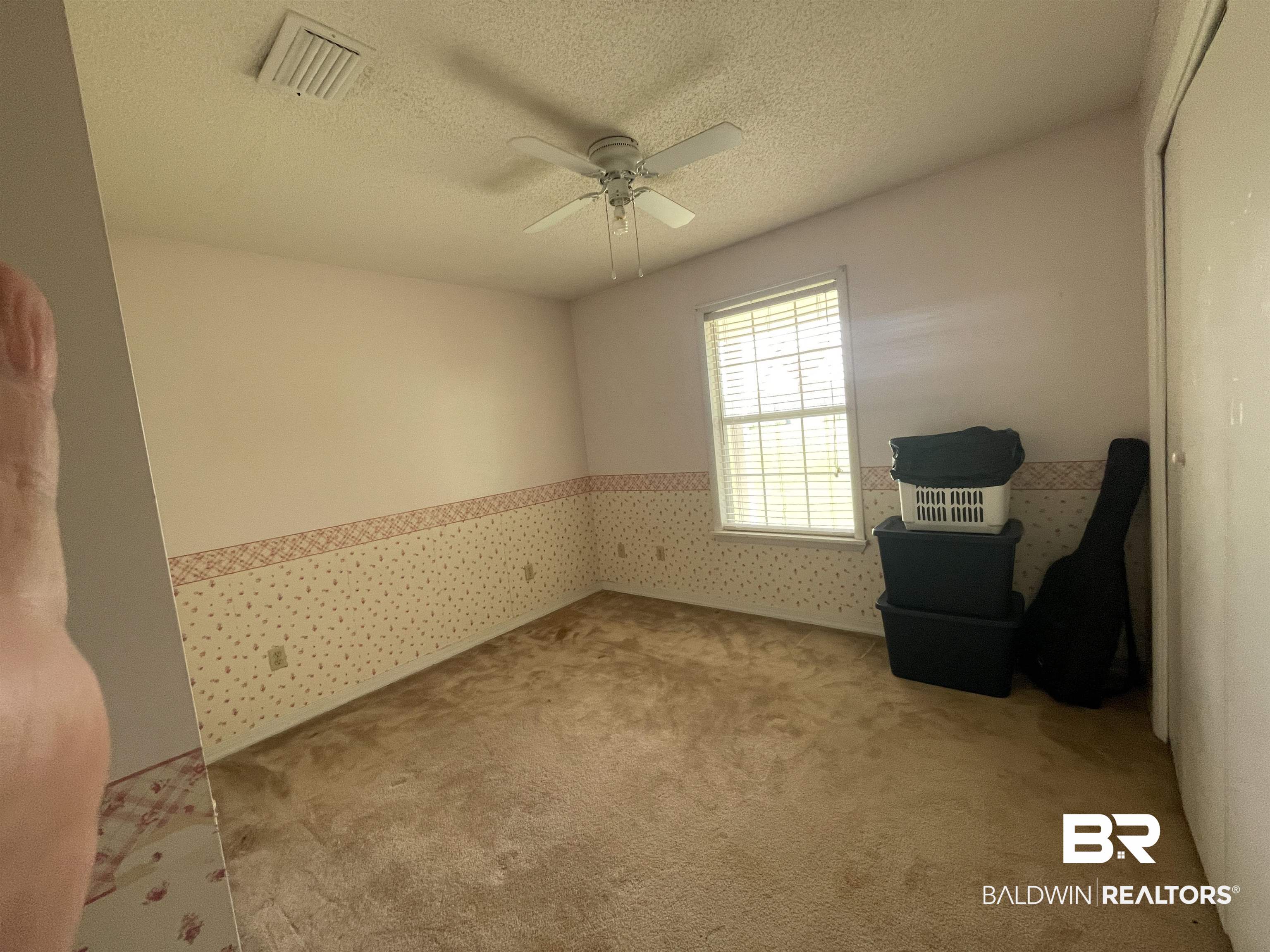 739 Smithfield Road Atmore, AL 36502 - Photo 8 of 18 Living area featuring a textured ceiling, wallpapered walls, a wainscoted wall, visible vents, and a ceiling fan