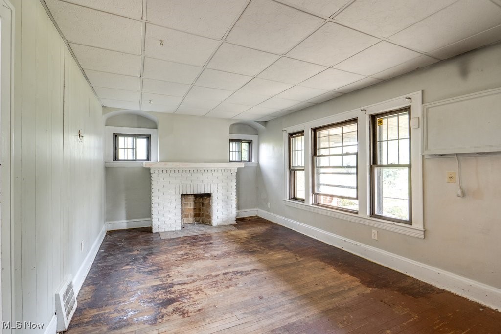 1618 Catalpa Road Cleveland, OH 44112 - Photo 9 of 33 Unfurnished living room with a drop ceiling, dark wood finished floors, and a brick fireplace