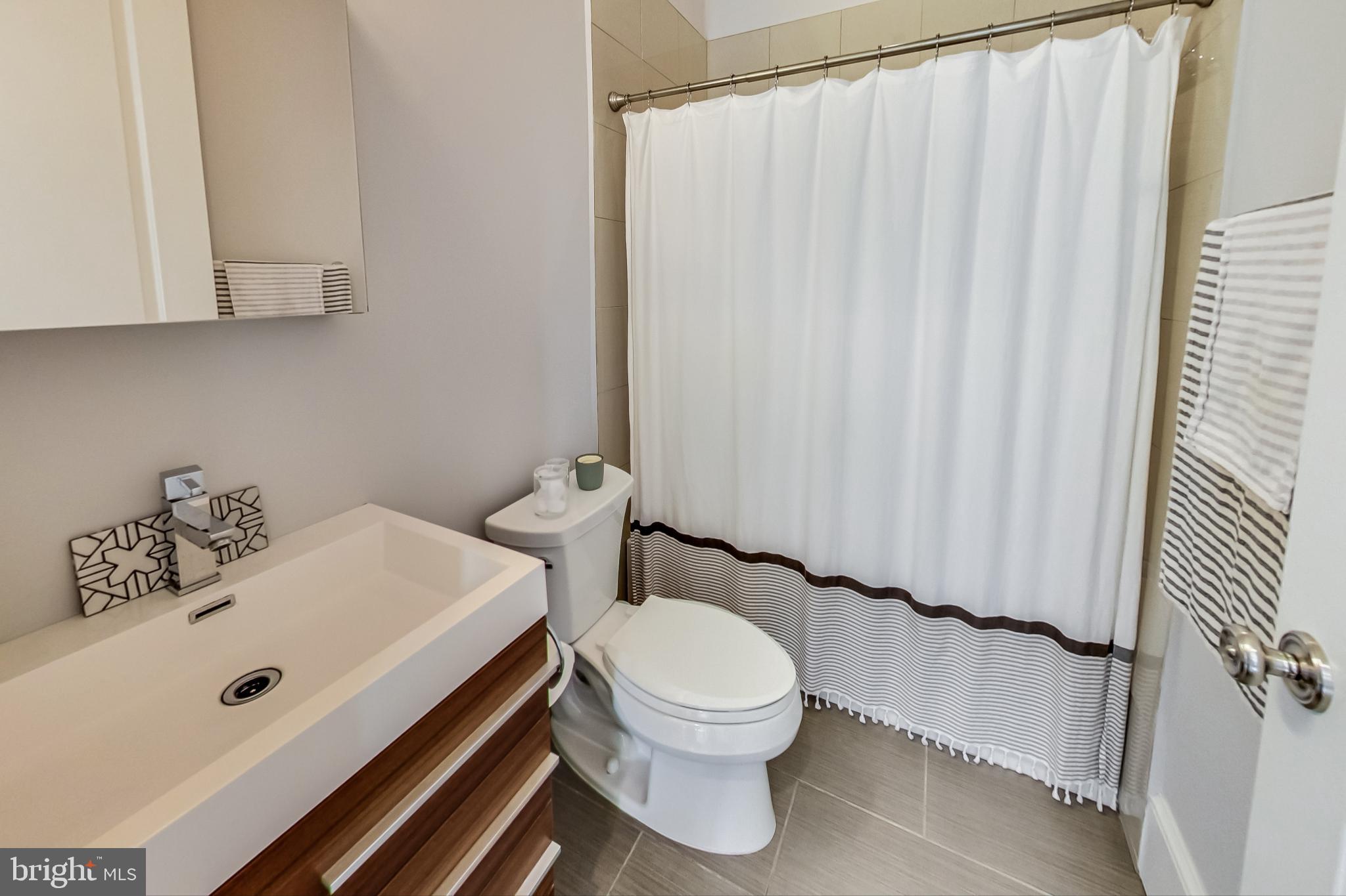 3324 18th Street Northwest, Unit 9 Washington, DC 20010 - Photo 28 of 44 a bathroom with a sink a toilet and shower curtain
